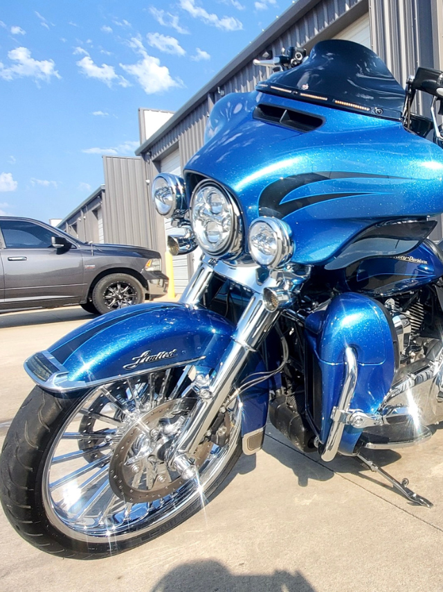 A blue harley davidson motorcycle is parked in front of a building