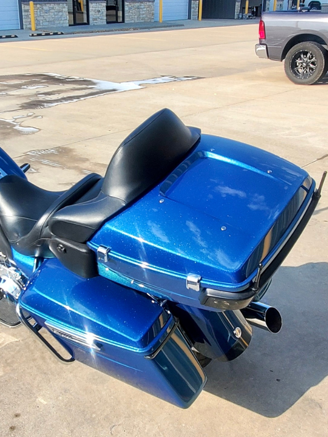 A blue harley davidson motorcycle is parked in a parking lot