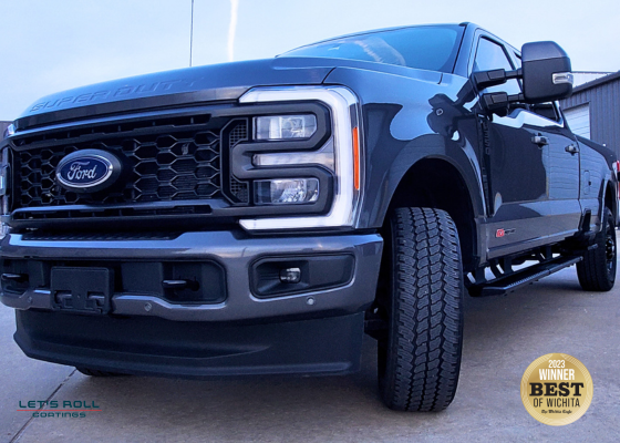 A black ford truck is parked on the side of the road.