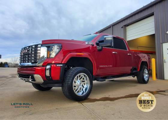 A red pickup truck is parked in front of a garage door.