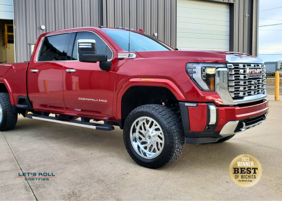 A red gmc truck is parked in front of a garage door.