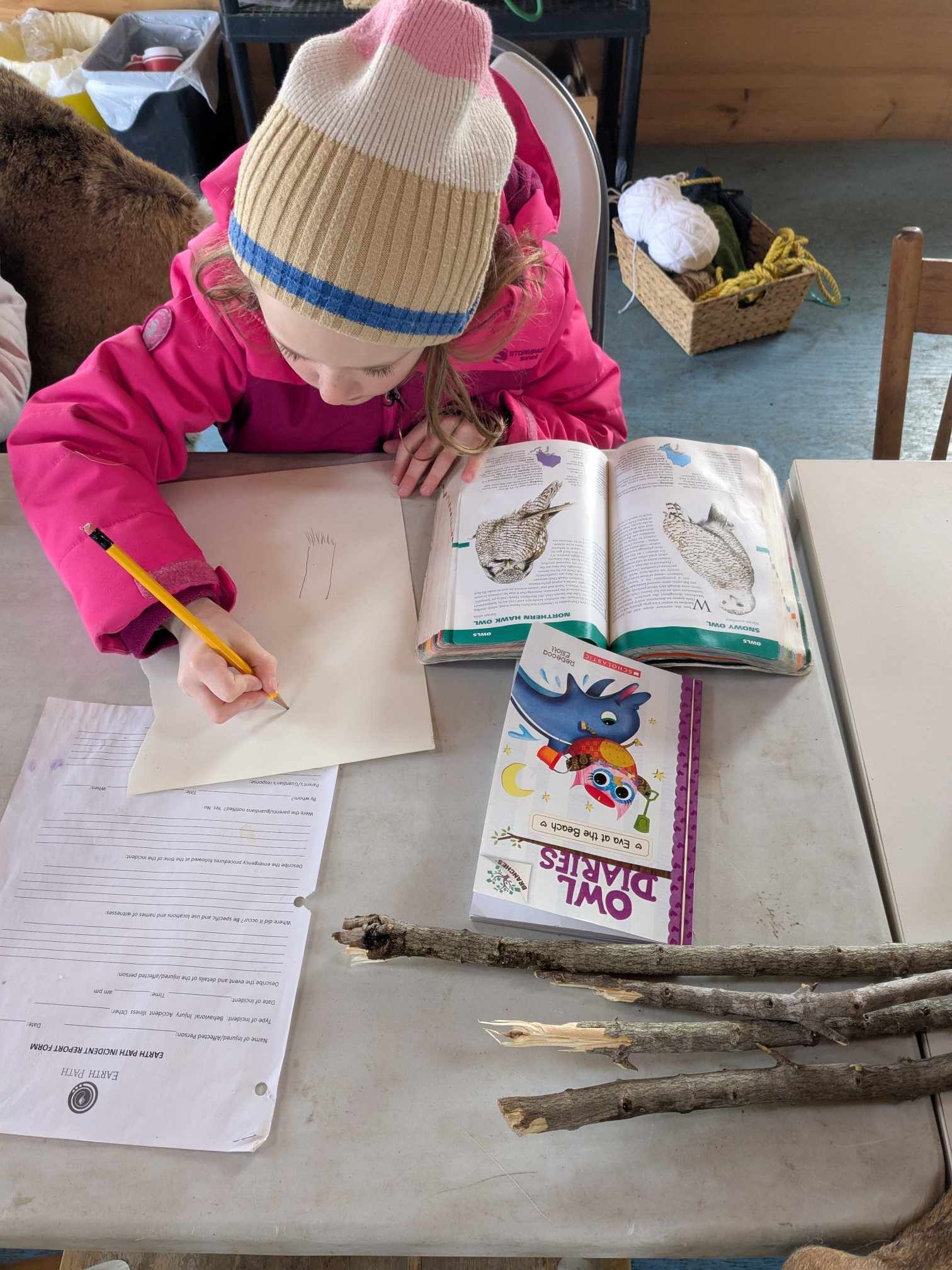 A little girl is sitting at a table writing in a notebook.