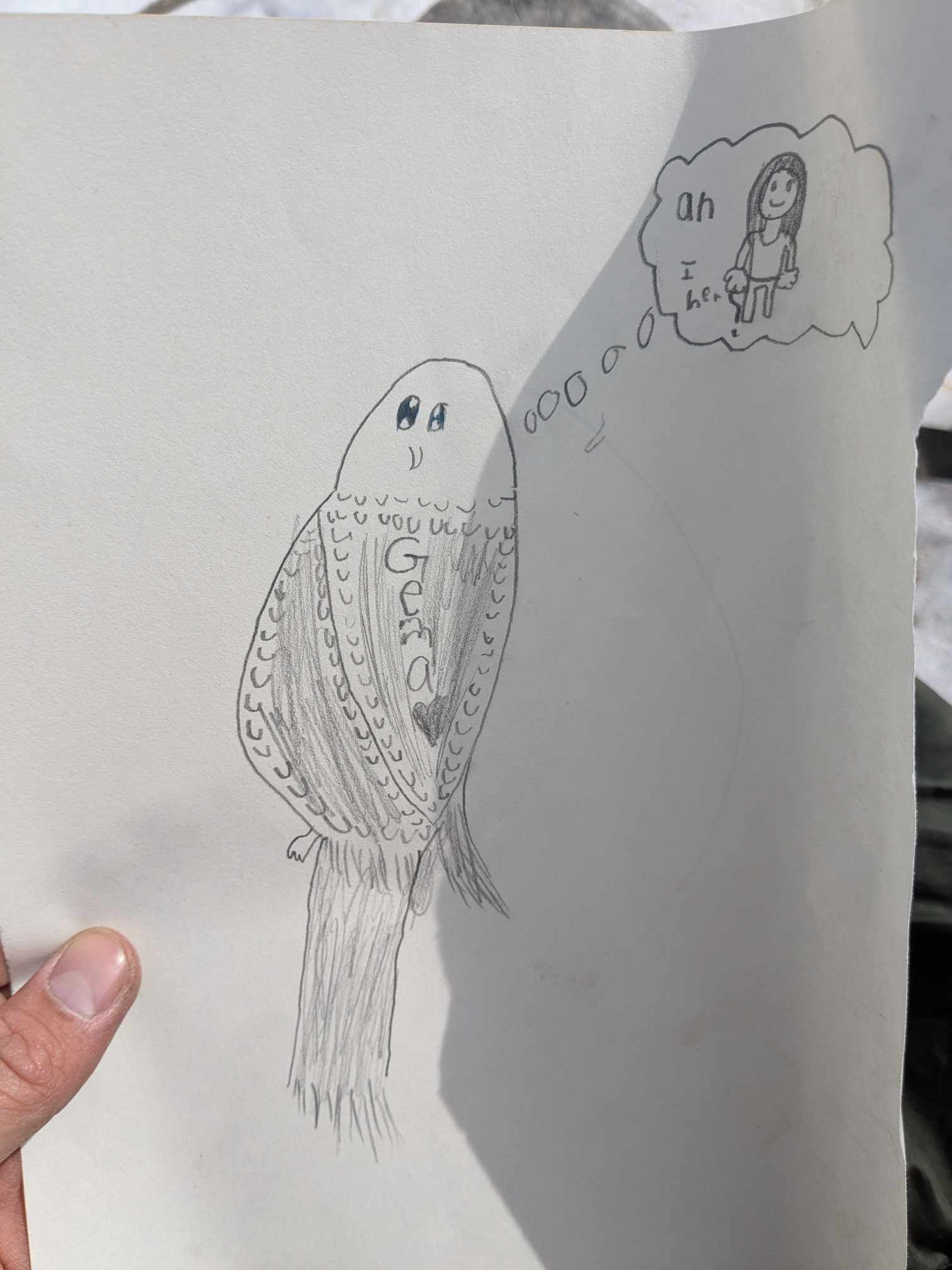 A person is holding a piece of paper with a drawing of a bird on it