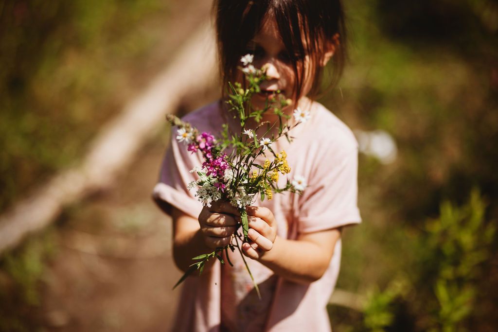 A little girl is holding a bouquet of flowers in her hands.