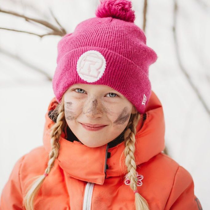 A little girl wearing a pink hat and an orange jacket