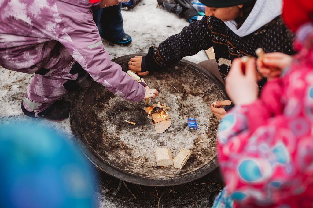 A group of children are playing with fire in a fire pit.