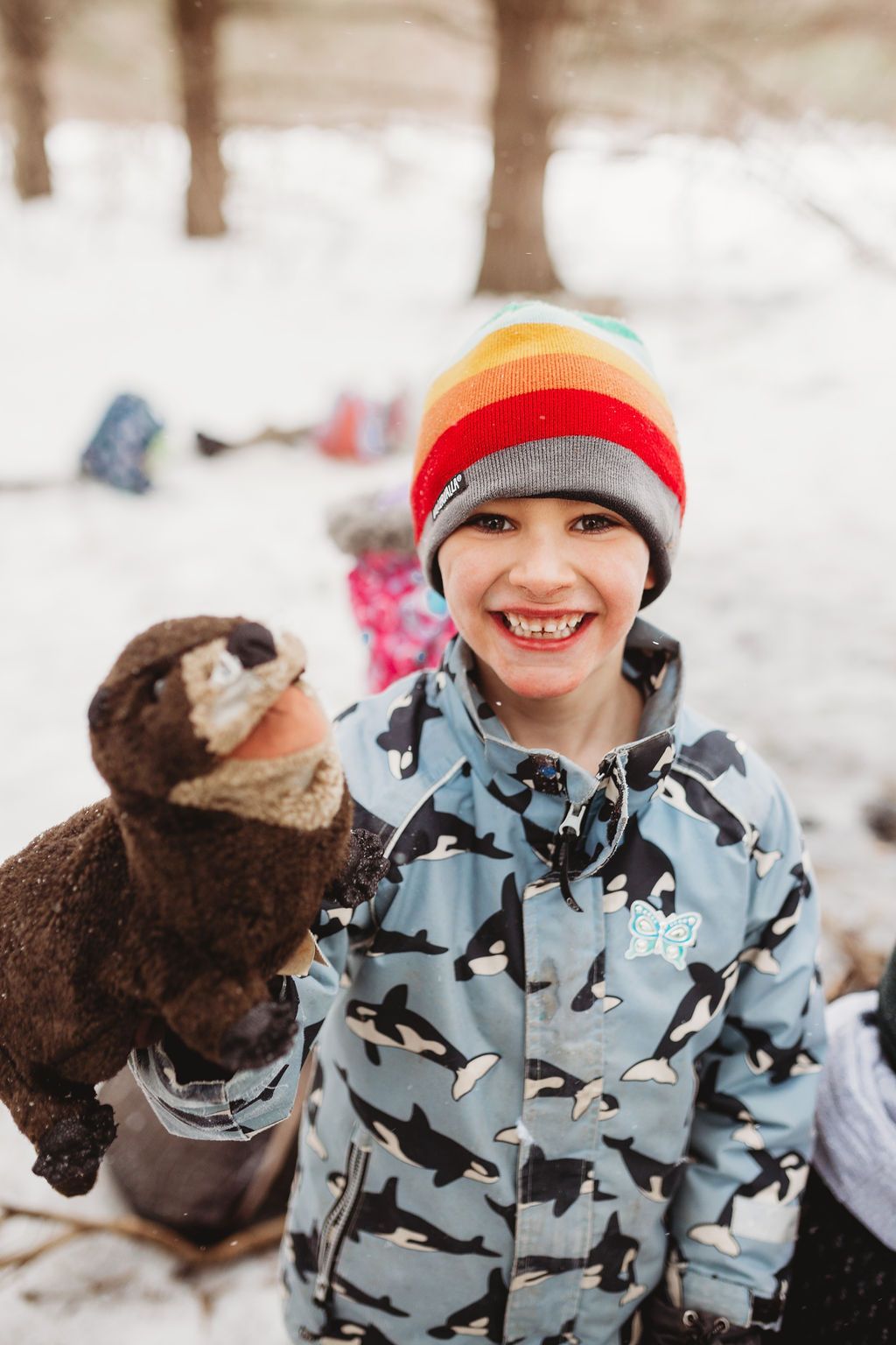 A young boy is holding a stuffed animal in the snow.
