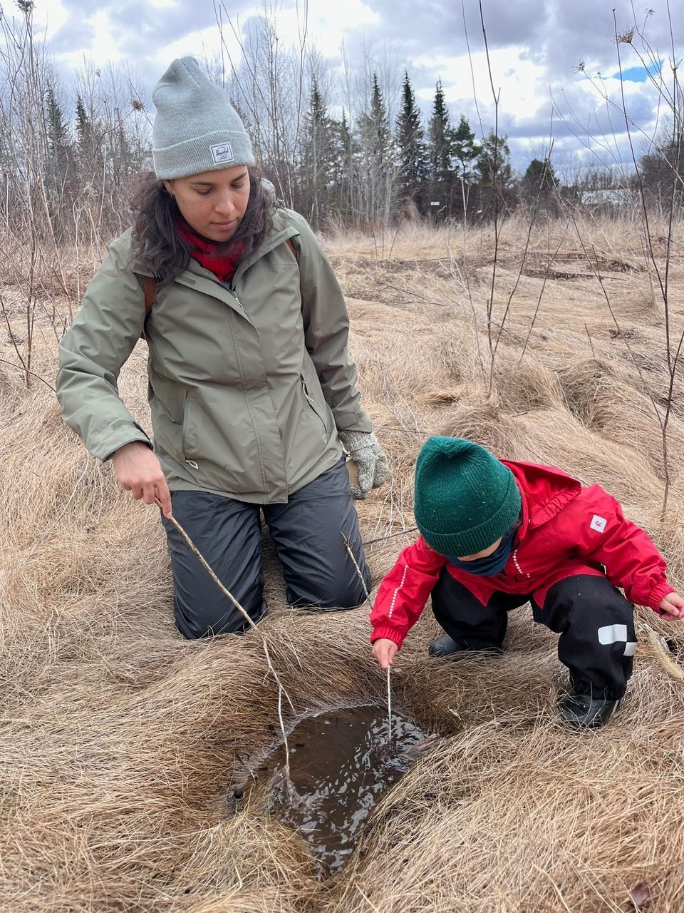 A woman and a child are kneeling in the dirt in a field.