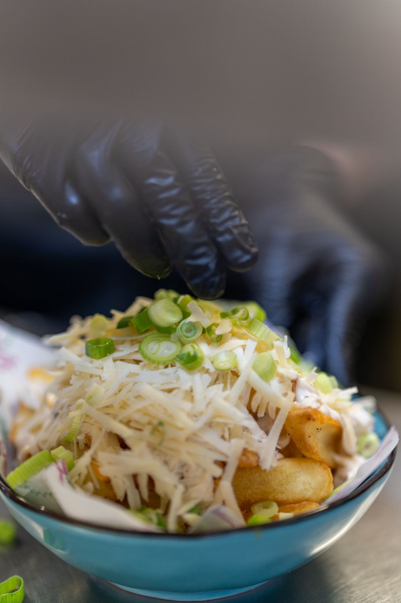 Een persoon voegt groene uien toe aan een kom eten.