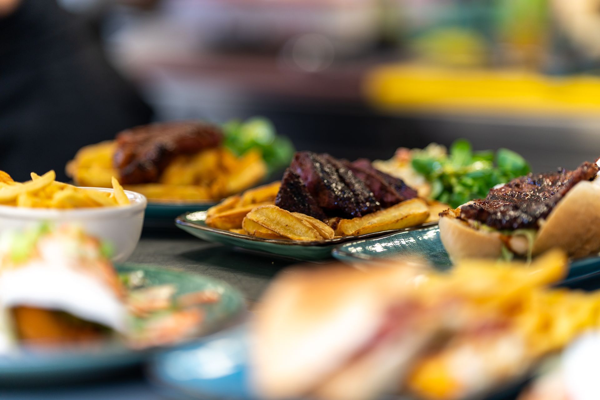 Een tafel vol borden met eten, waaronder broodjes en frietjes.