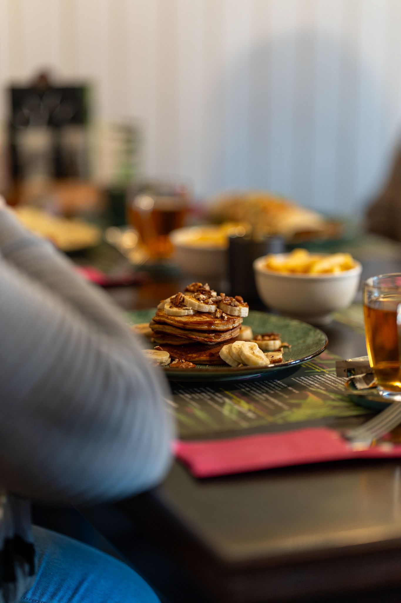 Een persoon zit aan een tafel met een bord pannenkoeken erop.