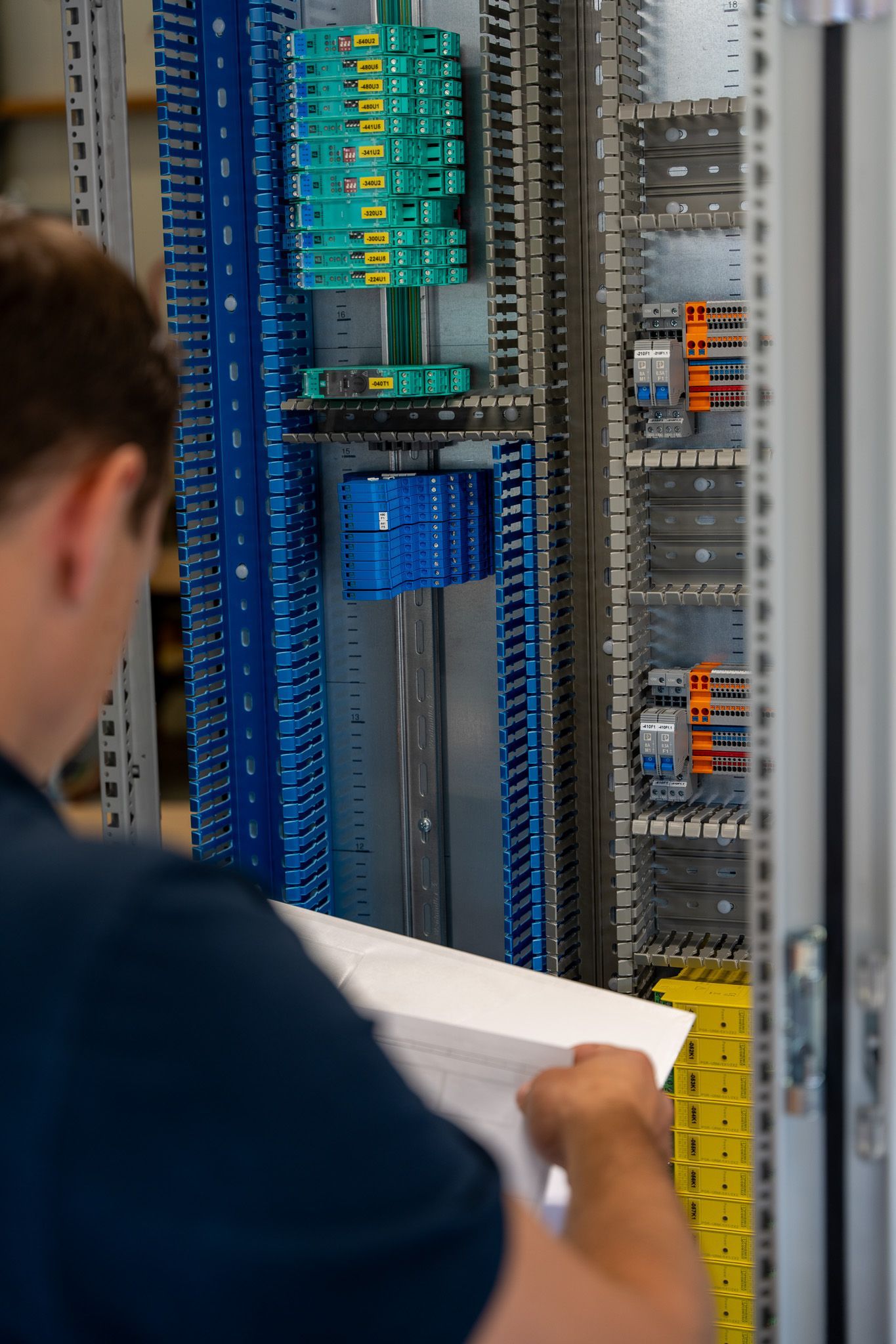 Een man werkt aan een elektrisch paneel in een fabriek.