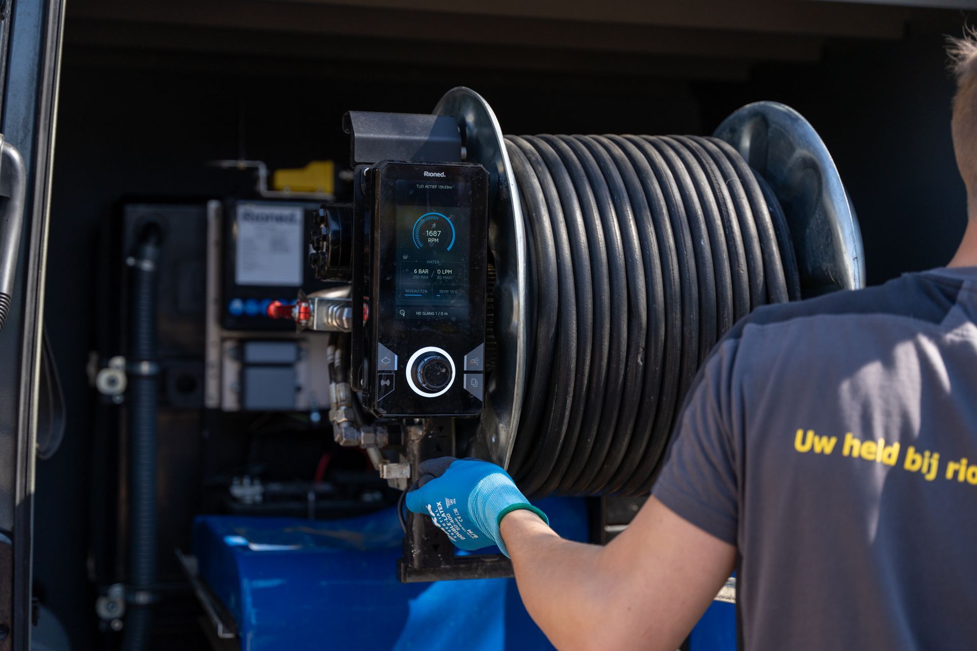 Een man houdt een grote slang voor een machine.