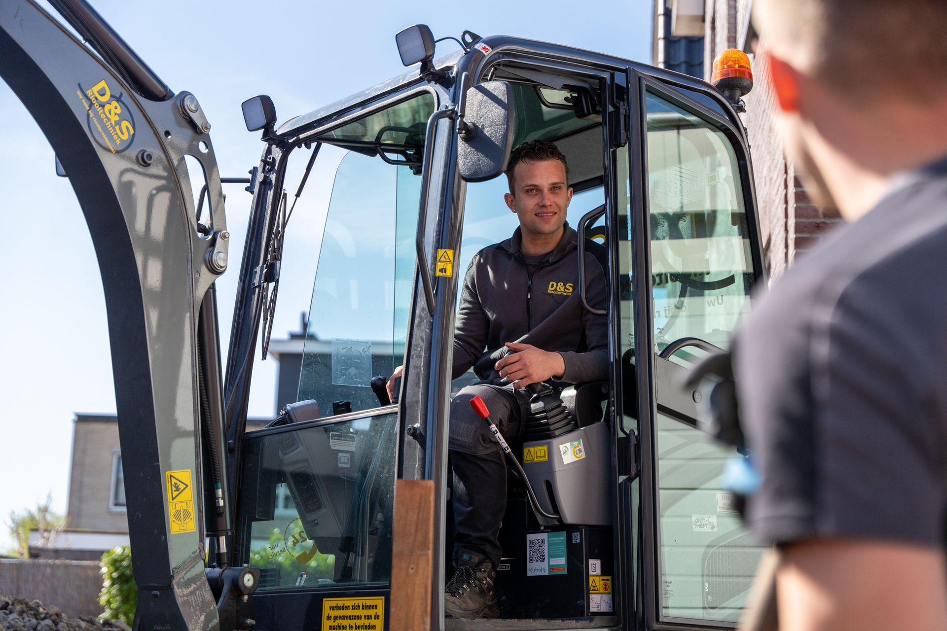 Een man zit op de bestuurdersstoel van een bouwvoertuig.