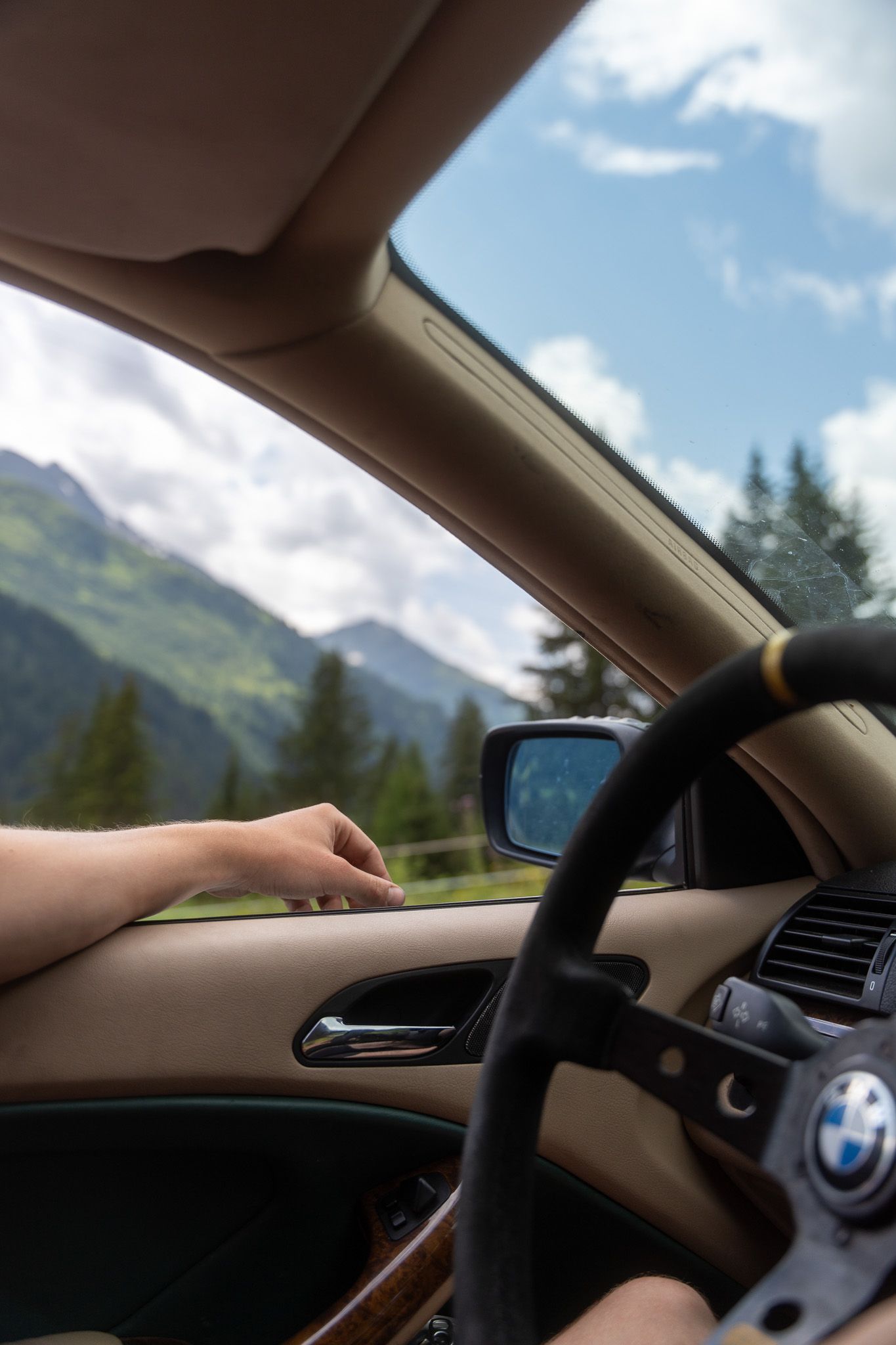 Een persoon rijdt in een bmw met bergen op de achtergrond