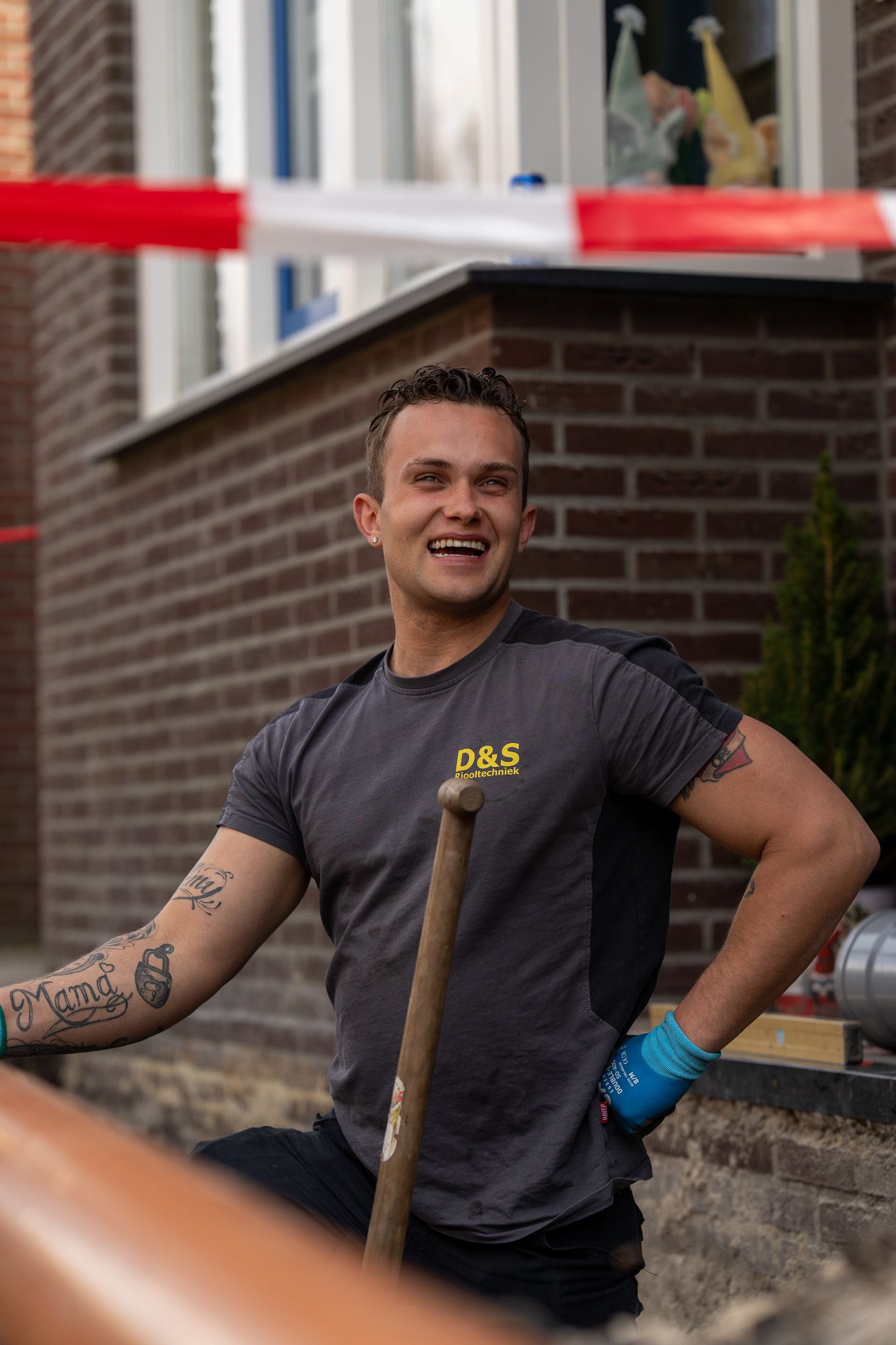 Een man houdt een schop vast voor een bakstenen gebouw.