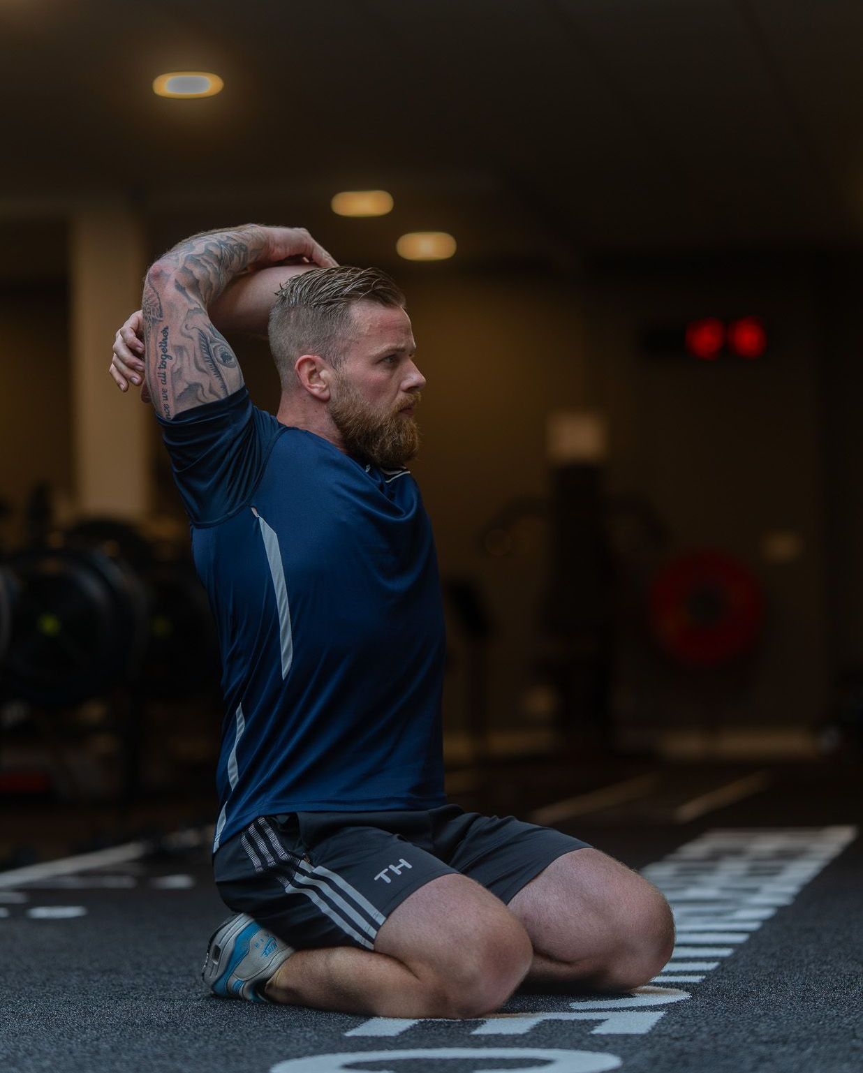 Een man knielt in een sportschool en strekt zijn armen.
