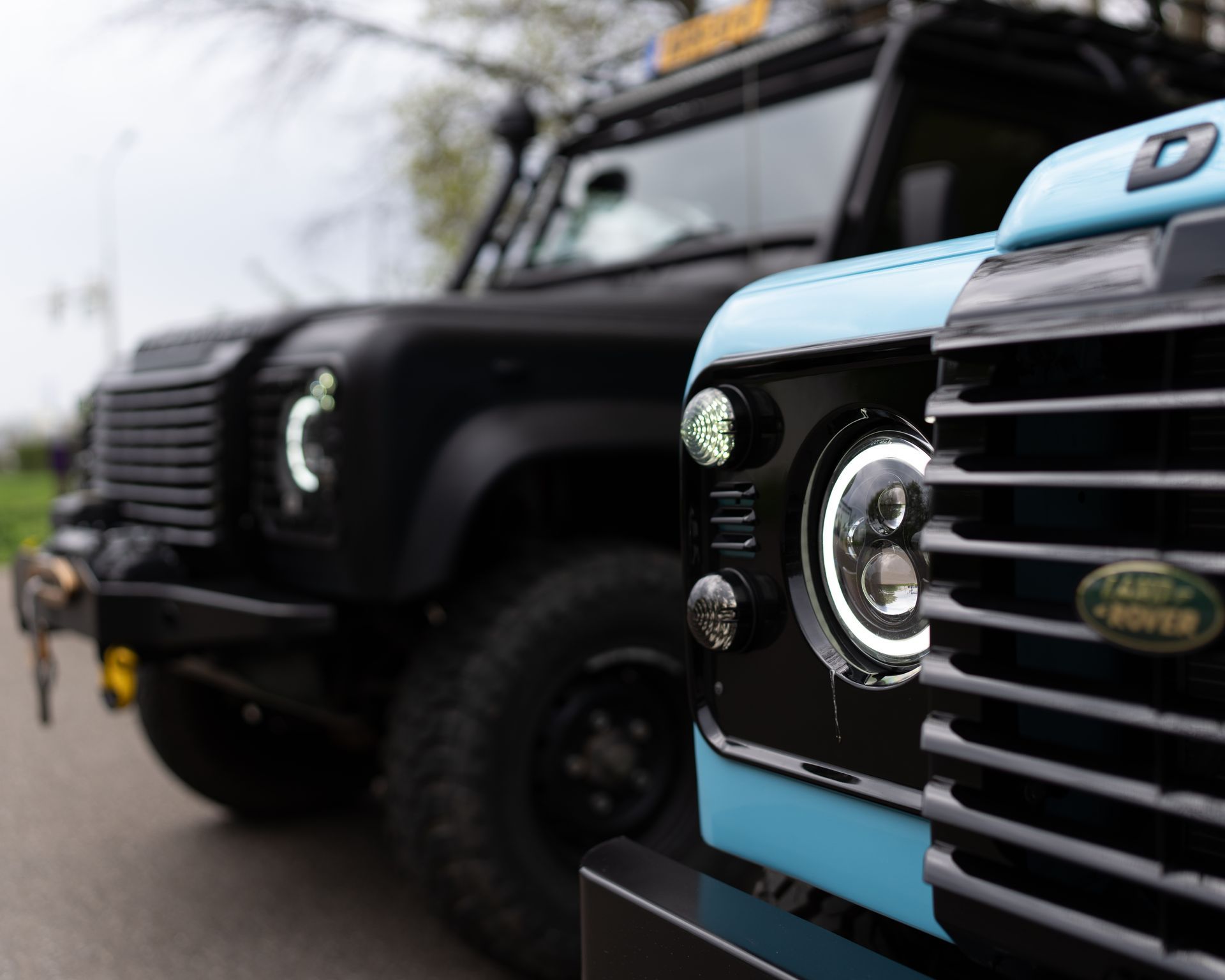 Twee Land Rover Defenders staan ​​naast elkaar op een weg geparkeerd.