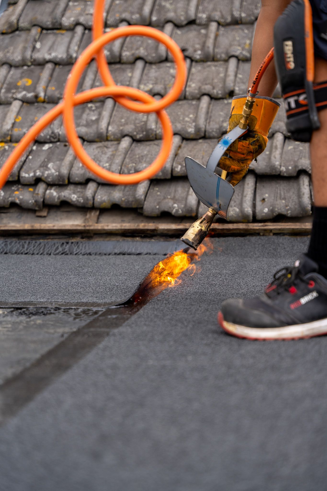 Een persoon gebruikt een brander op het dak