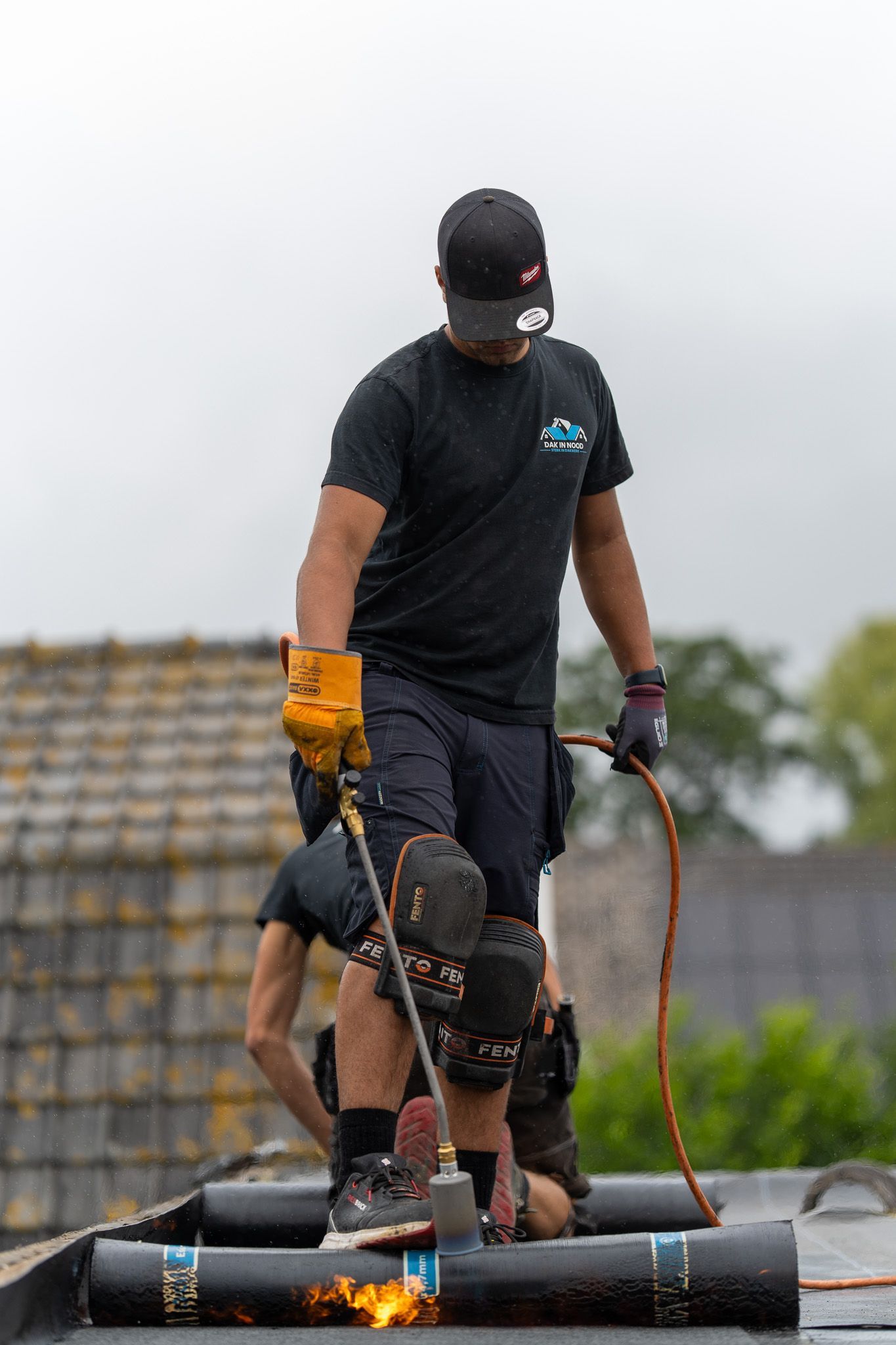 Een man staat op een dak met een fakkel in zijn handen.