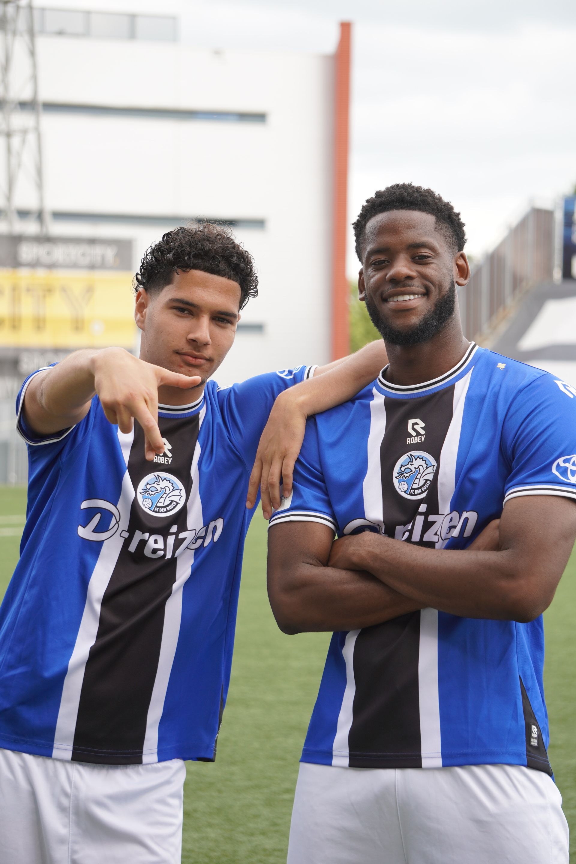 Twee jonge mannen staan ​​naast elkaar op een voetbalveld.