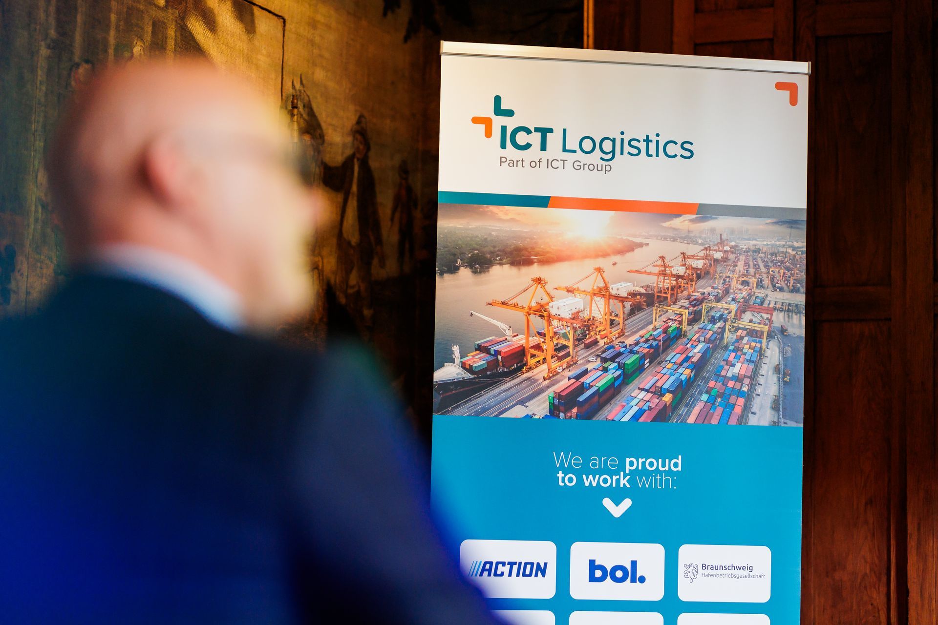 Een man staat voor een bord met de tekst ict logistics