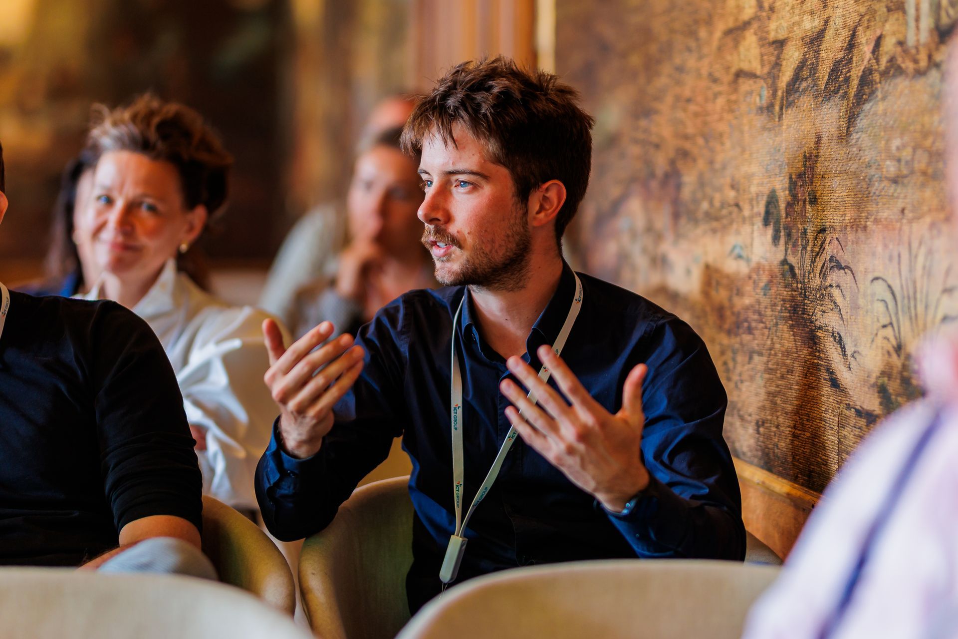 Een man zit op een stoel en praat met een groep mensen.