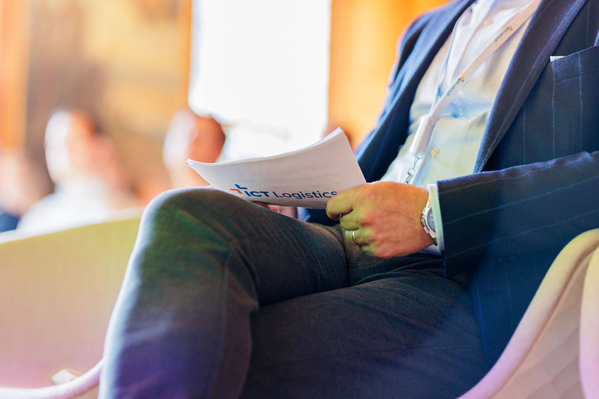 Een man in pak zit op een stoel en houdt een stuk papier vast.