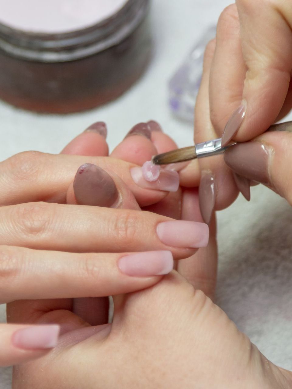 A woman is getting her nails painted with a brush.