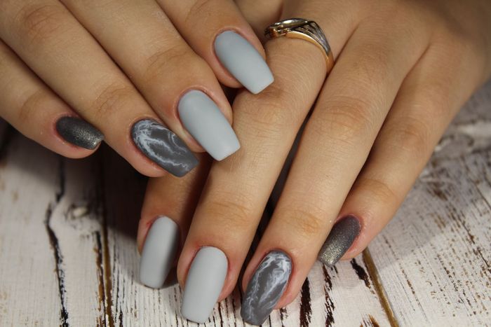 A close up of a woman 's nails with a ring on her finger.