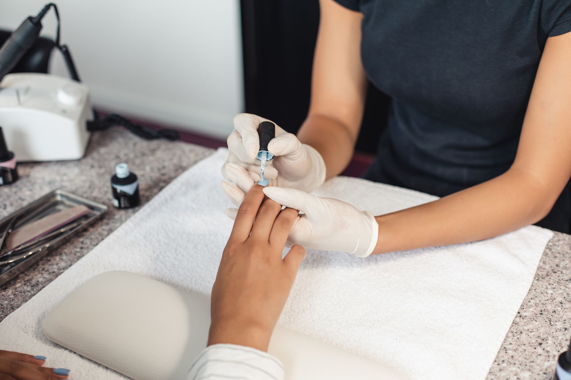 A woman is getting her nails painted by a nail artist.