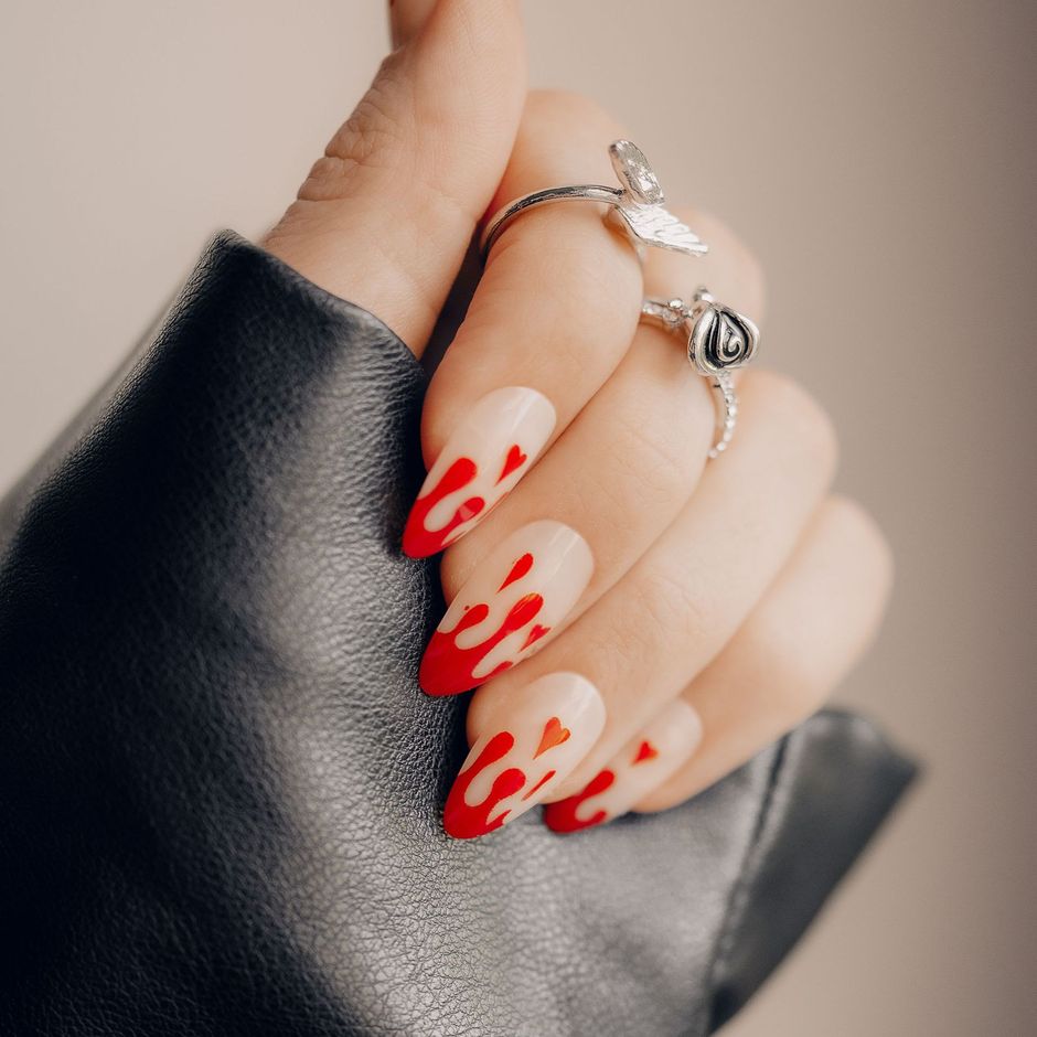 A woman 's hand with red nails and a ring on her finger