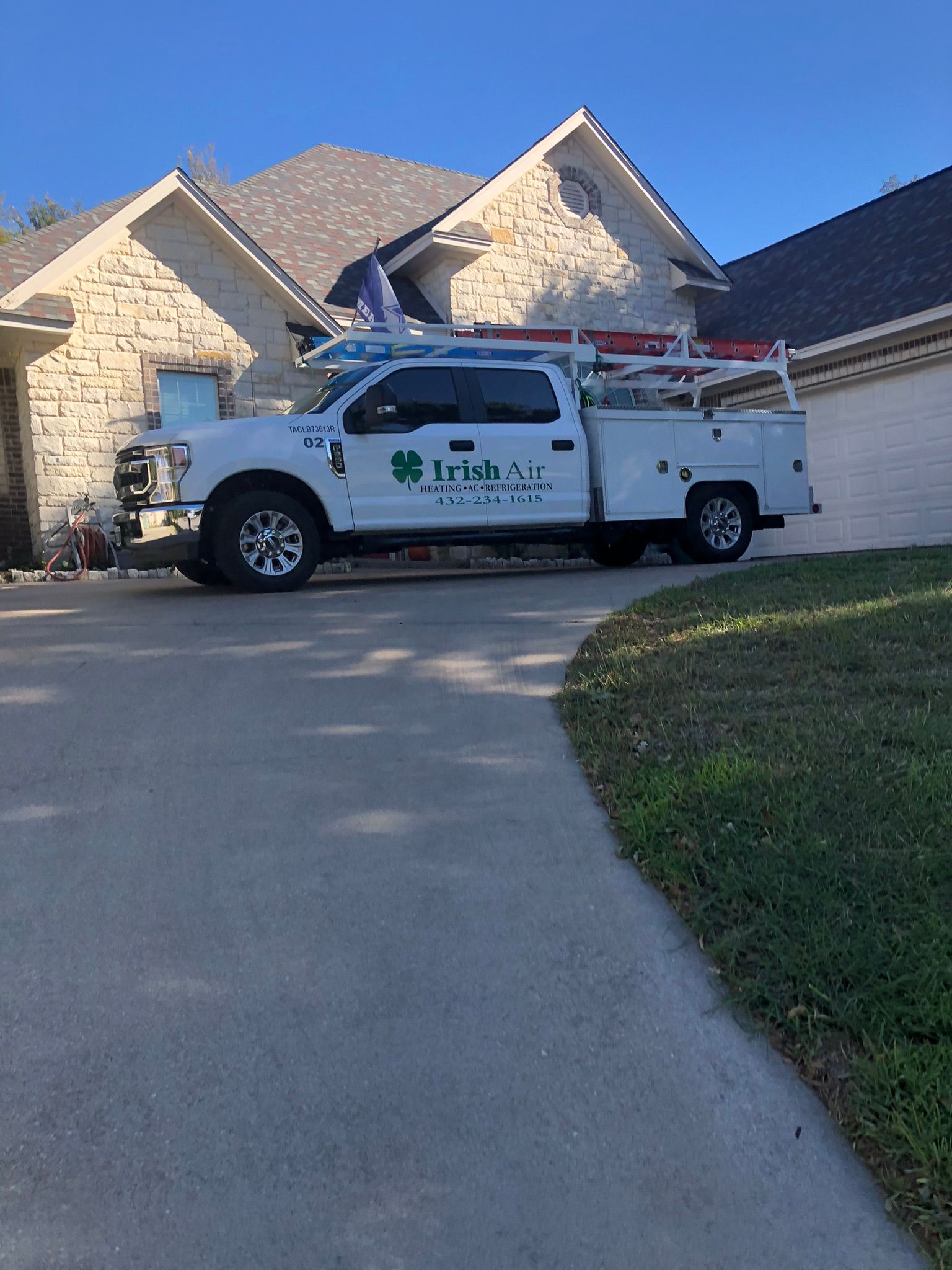 A white truck is parked in front of a brick house.