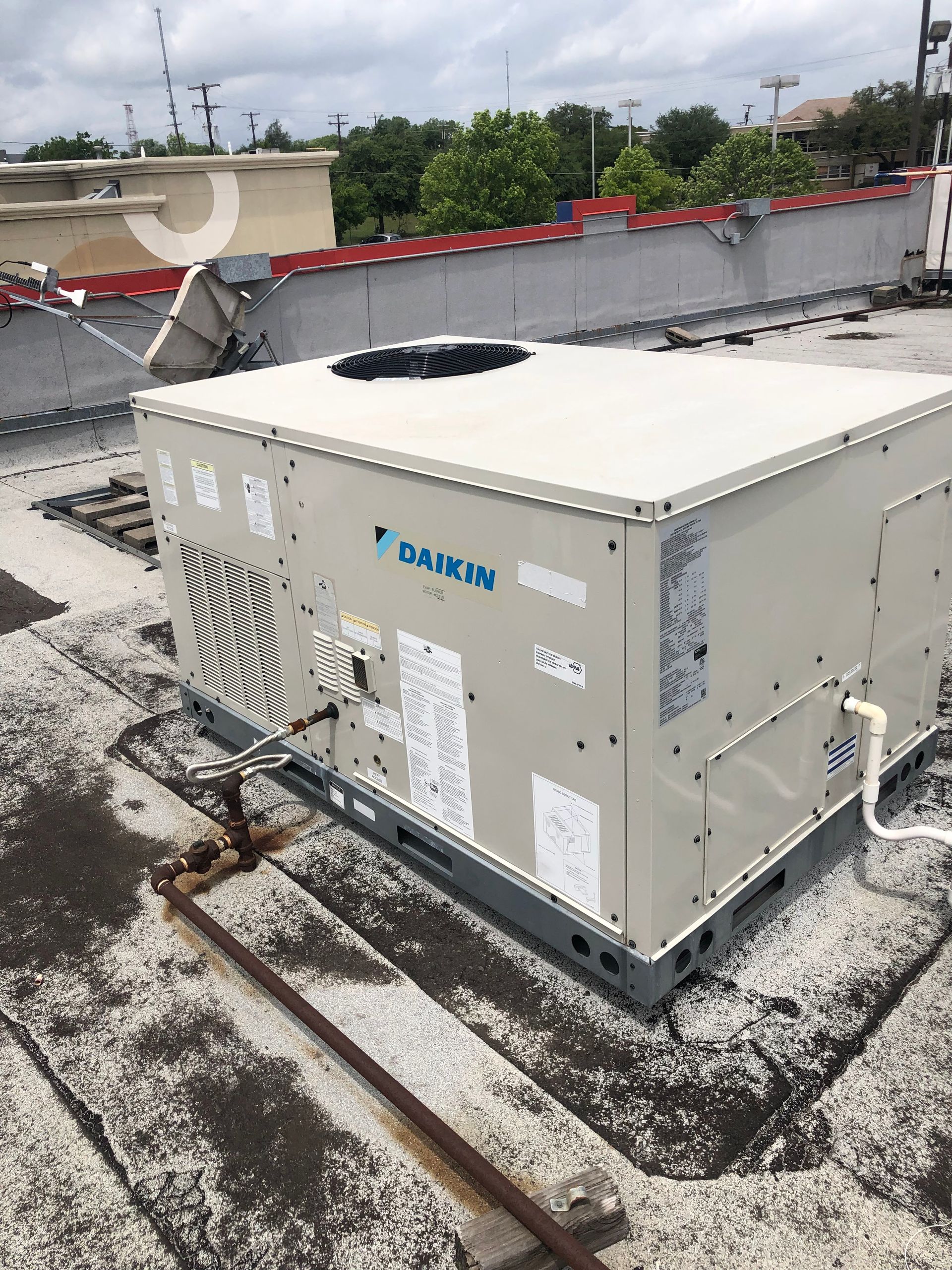 A daikin air conditioner is sitting on top of a roof.