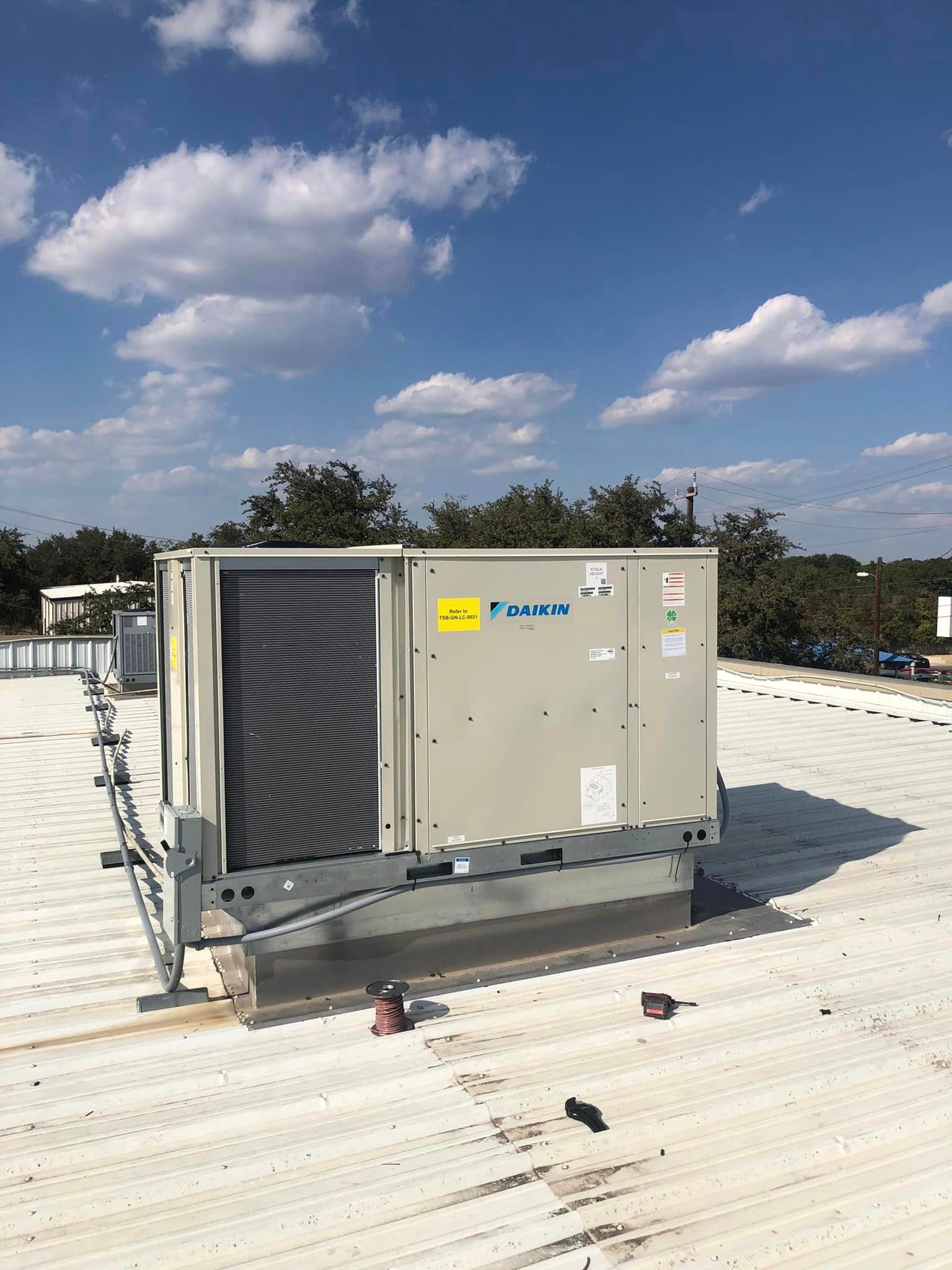 A large air conditioner is sitting on top of a white roof.
