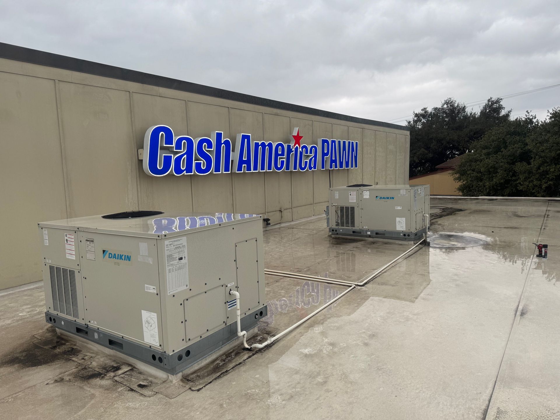 A stainless steel ice maker is sitting in a garage next to a refrigerator.