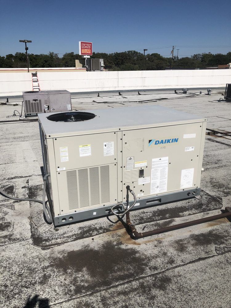 A daikin air conditioner is sitting on top of a roof.