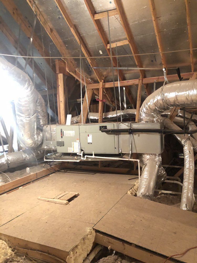 There are a lot of pipes hanging from the ceiling in the attic.