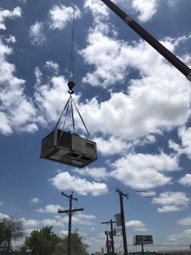 An air conditioner is being lifted by a crane in the sky