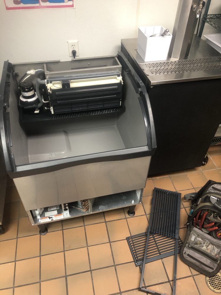A stainless steel refrigerator is sitting on a tiled floor in a kitchen.