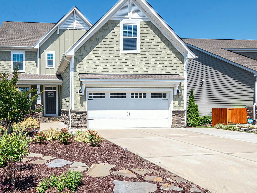 A large house with a white garage door and a walkway leading to it.