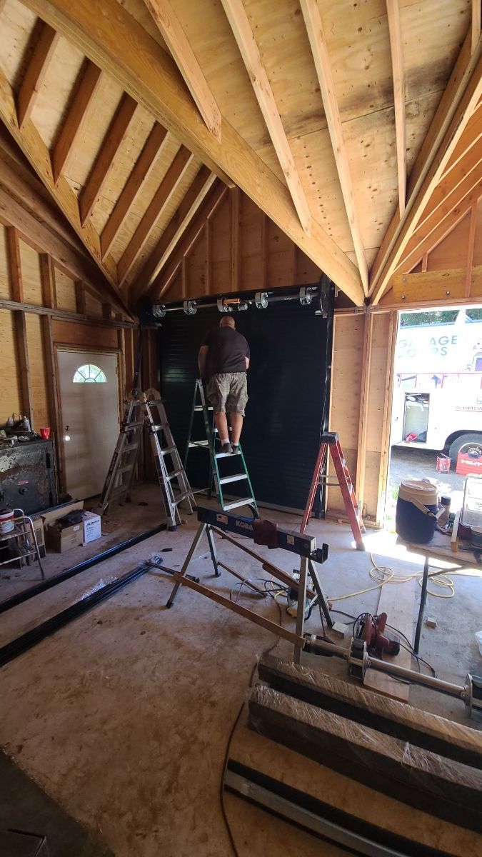 A man is standing on a ladder in a wooden garage.