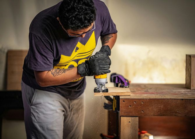 Person using a power drill on a wooden workbench in a workshop
