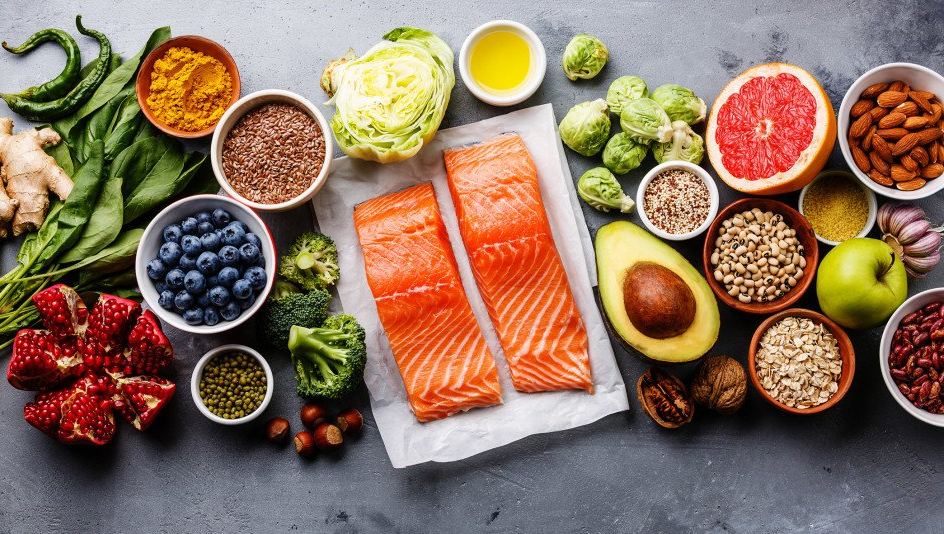 Assortment of fresh foods including salmon, fruits, vegetables, grains, and nuts.