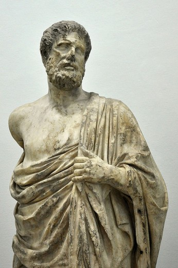 Marble statue of a man wearing a draped garment, holding fabric, with a beard and serious expression.