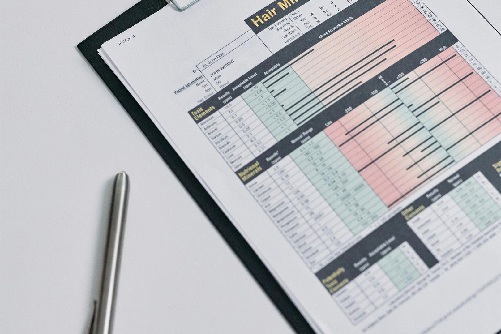 A clipboard with a spreadsheet on it and a pen on a table.