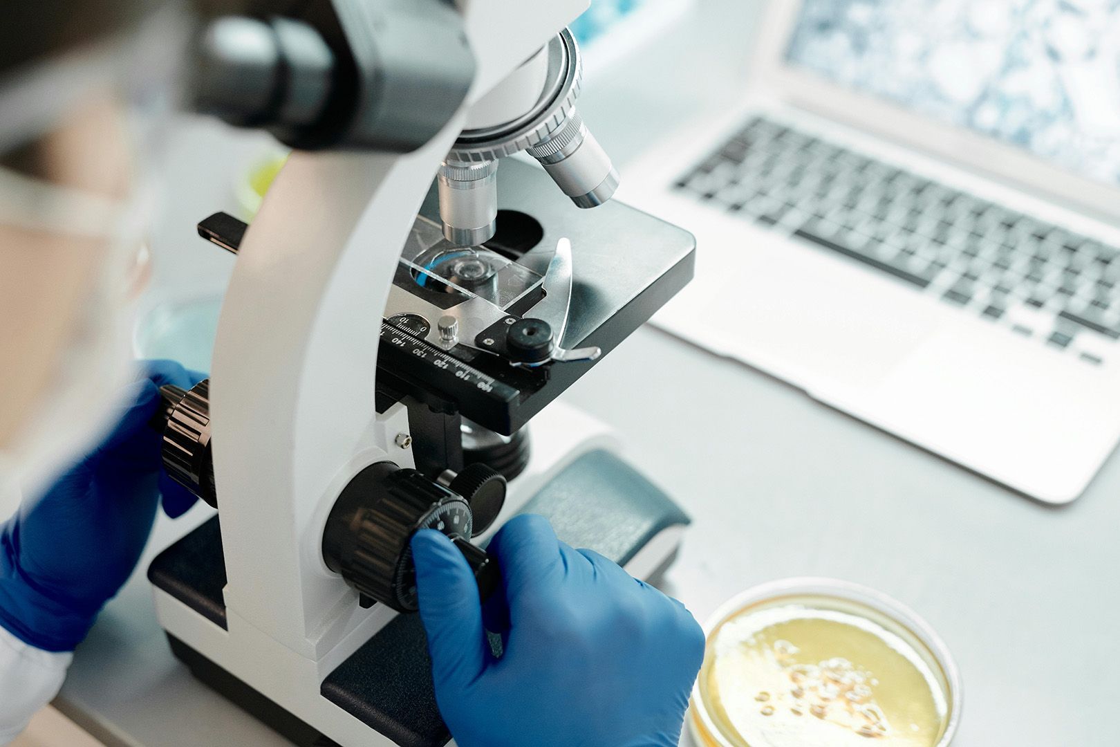 A person is looking through a microscope in a lab.