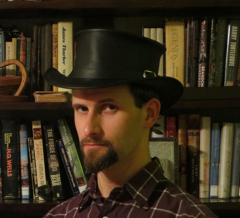 Photo of William C Tracy, who is a Caucasian man with short dark hair, a goatee and a black top hat. 