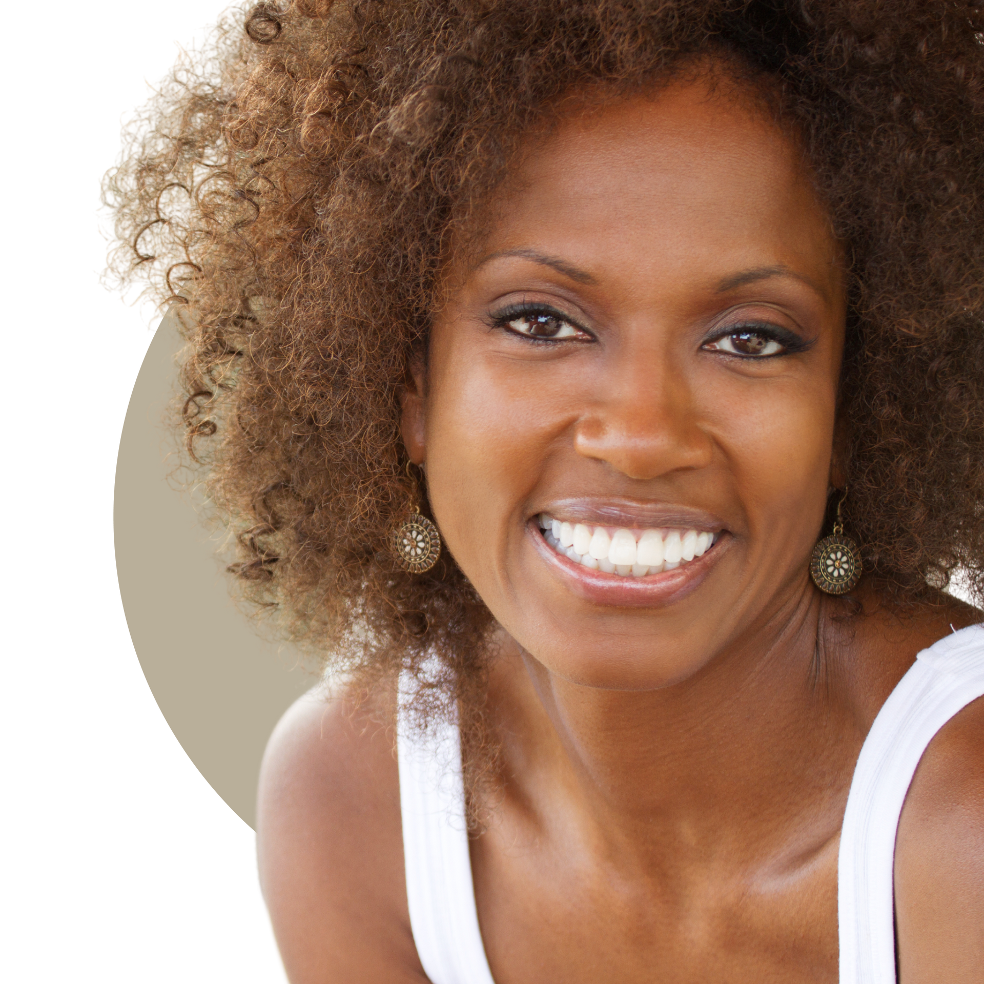 A woman with long curly hair is smiling and touching her face.