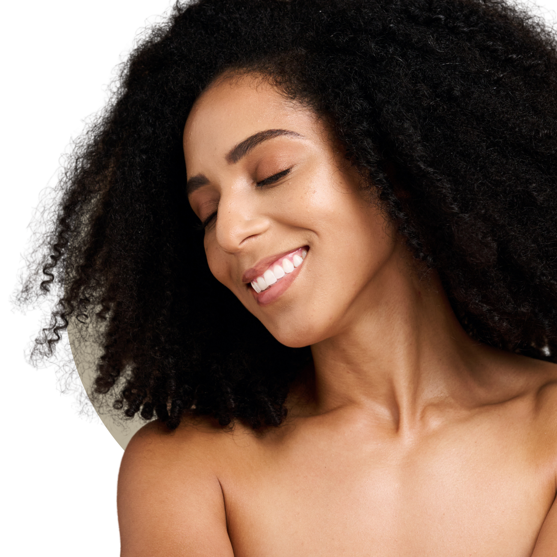 A woman with long curly hair is smiling and touching her face.